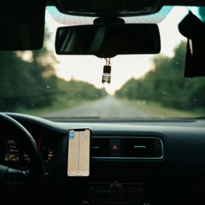View of a car interior with a GPS on a scenic road during daytime travel.