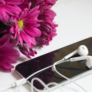 Close-up of pink flowers with a smartphone and earphones for a modern aesthetic.